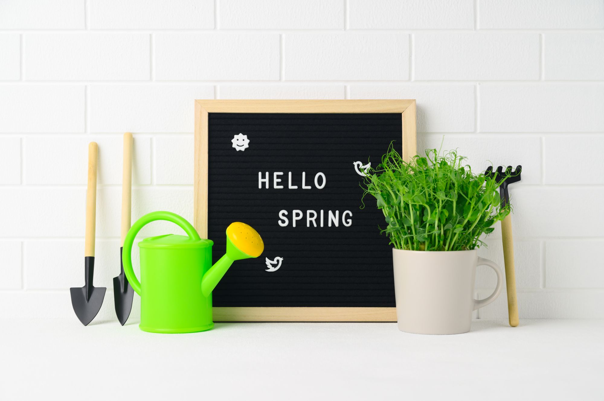 A small letterboard welcoming spring with gardening toys laid out around it