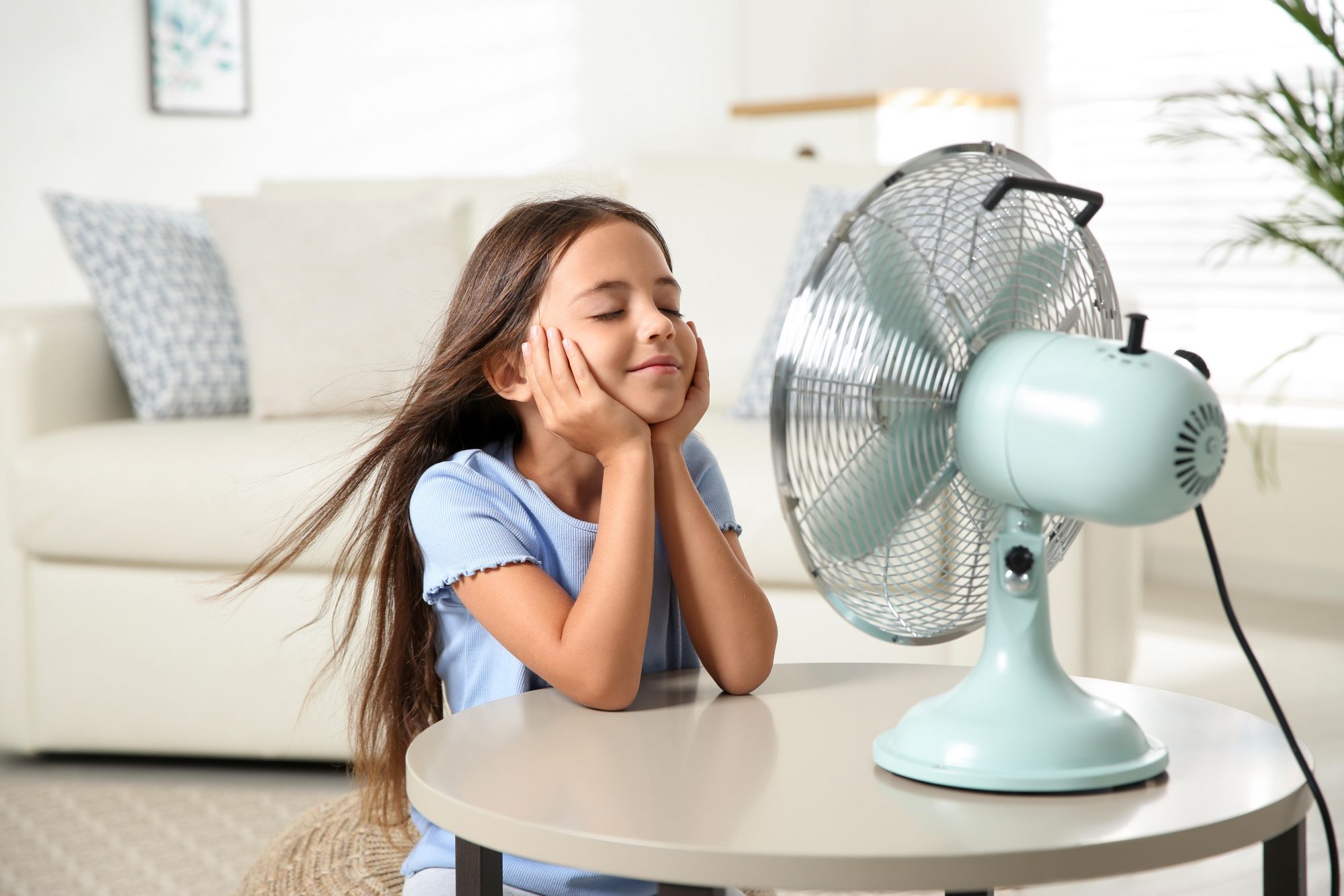 Young girl keeping cool with a fan
